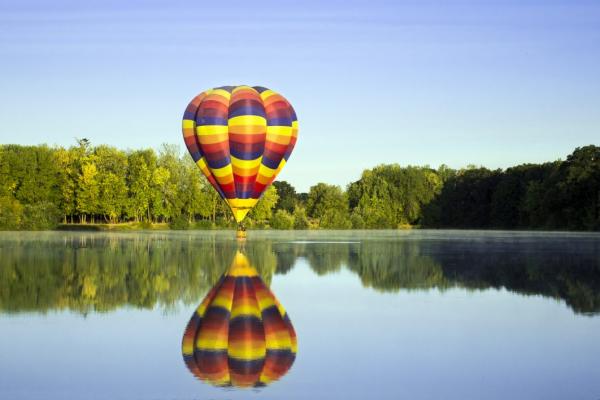 Negative space hot air balloon over calm lake 1062x708